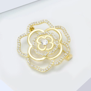 Detailed macro of gold hollow flower brooch featuring micro-set cubic zirconia crystals