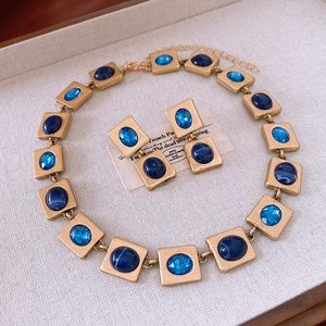 Detail of vintage gold necklace and earrings with square blue gemstone settings