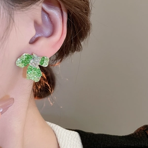 Close-up of green petal clover earring with gold plating and zircon stud on ear