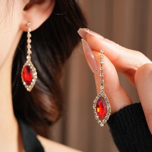 Close-up of red gemstone teardrop tassel earring with elegant gold finish on a model