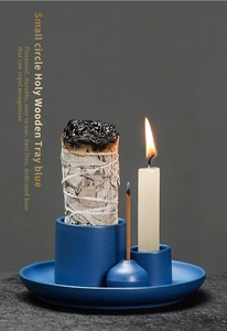 Blue ceramic tray set for sage and incense with a burning candle on a dark surface