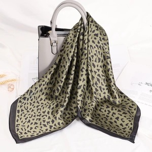 Dettaglio del foulard in raso leopardato verde oliva drappeggiato su una borsa grigia