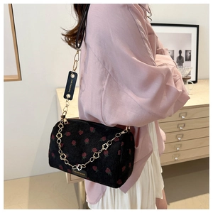 Detail of strawberry corduroy crossbody bag with floral metal chain strap and logo
