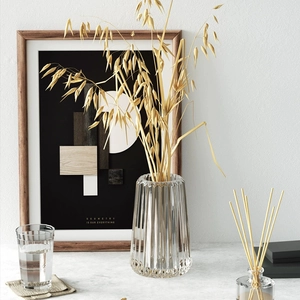 Detailed view of modern vertical striped glass vase with dry oat stalks in home setting