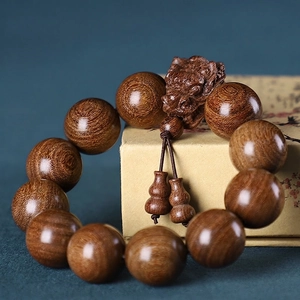 Macro detail of African Golden Sandalwood beads with hand-carved dragon and gourd charms