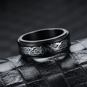 Macro shot of black titanium spinner ring featuring silver Celtic dragon pattern on leather
