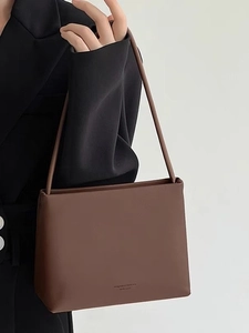 Elegant brown faux leather crossbody tote bag for women shown by a model on plain background
