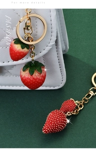 Primer plano de dijes de fresa con detalles en resina roja y diamantes de imitación
