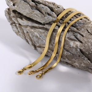 Three golden stainless steel flat snake bone necklaces on rock with lobster clasp