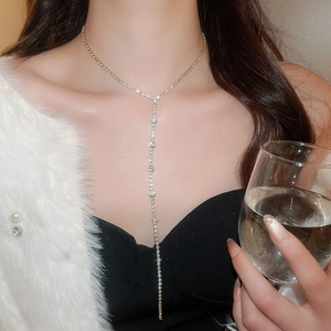 Close-up of a silver Y-shaped tassel necklace with sparkling rhinestones on a model
