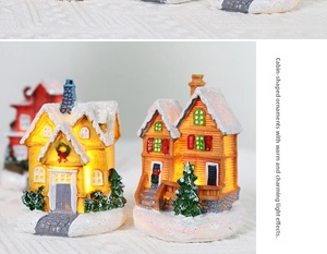 Detail of light-up resin Christmas miniature houses with snow-covered roofs and warm LED light
