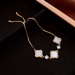 Detail of adjustable gold four-leaf clover bracelet with white shell and cubic zirconia