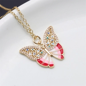 Macro shot of gold butterfly necklace featuring evil eye charms and pink enamel detail