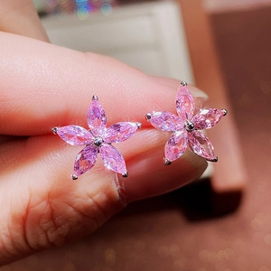 Macro shot of pink zircon five-petal flower stud earrings with silver metal claw setting
