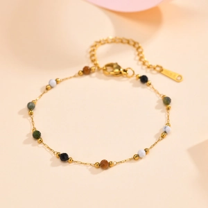 Detailed shot of a gold chain necklace featuring colorful natural stone beads and clasp