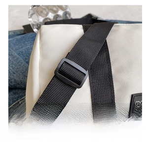 Detail of adjustable black nylon shoulder strap with plastic buckle on white nylon bag