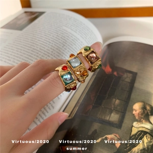 Detailed view of three vintage gold rings with colorful gemstones on a hand