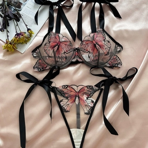 Flat lay of black mesh lingerie set with pink butterfly embroidery and satin ribbons