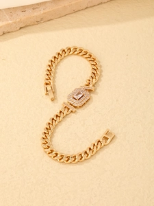 Close-up of golden Cuban chain bracelet with rectangular zircon inlay on sand texture