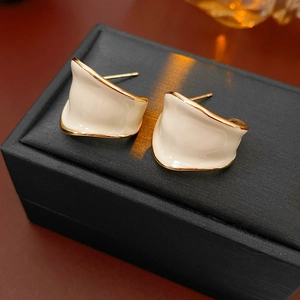 Dettaglio di orecchini a C in smalto bianco con placcatura in oro su portagioie nero