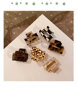 Top view of six mini acetate hair claws featuring leopard print and checkerboard patterns
