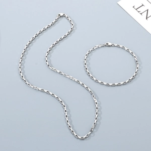Flat lay of minimalist silver stainless steel box chain necklace and bracelet set