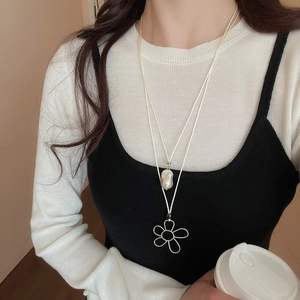 Close-up of double-layered necklace with baroque pearl and silver wire flower pendant