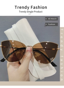 Close-up of metal cat eye sunglasses with brown lenses and a white leather case