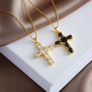 Cross pendant necklaces with gold chain and zircon inlay on white book with silk