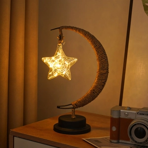 Moon shaped iron art LED lamp with twine wrap and hanging glass star on a round base