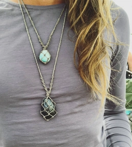 Close-up of model wearing two hand-woven net pouch necklaces with colorful crystal stones