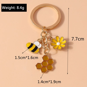 Detail of bee and sunflower keychain showing dimensions and weight of 8.4g on pink background