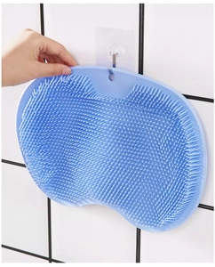 Blue silicone shower back scrubber hanging on white tiled wall with suction hook