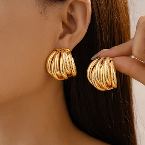 Close-up of model wearing gold multi-layered textured geometric hoop earrings