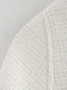 Close-up of cream-colored tweed poncho featuring intricate knit texture and seam detail