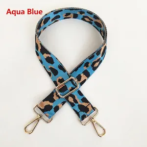 Detail of light blue leopard print bag strap with golden metal hooks and adjustable buckle