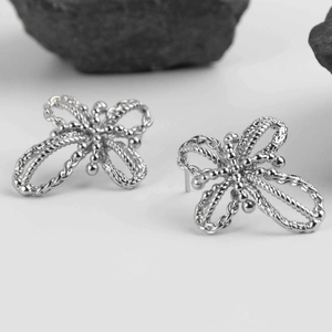 Silver bow stud earrings with hollow bead craftsmanship on a black textured stone