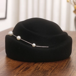 Détail du chapeau en laine noire avec décoration élégante de perles et chaîne en strass