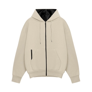 Détail d'un sweat à capuche beige en polaire avec cordon noir et poche zippée décorative