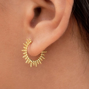 Close-up of golden beaded hoop earrings worn on an ear showing fine craftsmanship