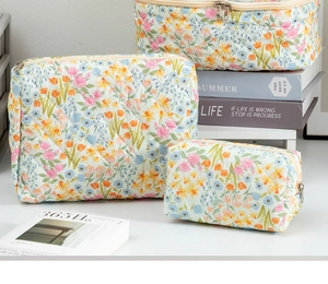 Three-piece set of quilted floral cosmetic bags in various sizes with zipper closure