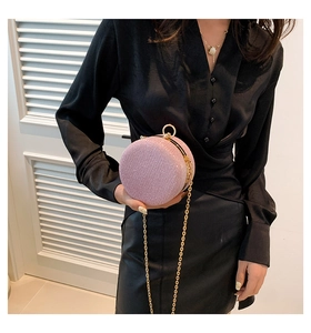 Détail d'une pochette ronde rose pailletée avec chaîne dorée et fermoir en anneau