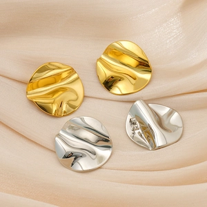 Détail macro de boucles d'oreilles clous plissées en métal doré et argenté sur soie