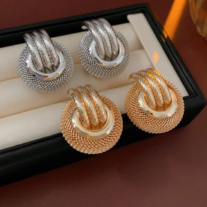 Detailed shot of gold and silver metallic mesh ball earrings with twisted rings in a box
