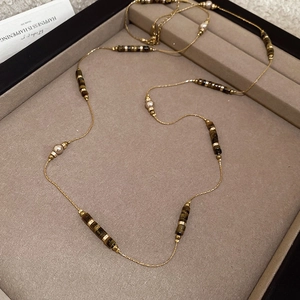 Detail of tiger eye beads and pearls on a gold-plated stainless steel necklace