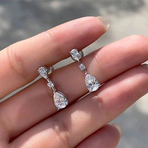 Close-up of elegant silver teardrop earrings with sparkling pear-cut crystals in hand