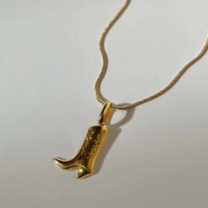 Macro shot of 18k gold plated cowboy boot pendant necklace with detailed textures