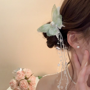 Detail of light green mesh butterfly hair clip with long white pearl tassels and beads