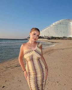 Detail of slim fit one shoulder dress with wavy print pattern in sunset beach setting