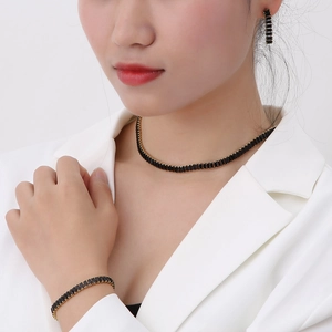 Detail of luxury gold-plated jewelry set with black rectangular stones on model
